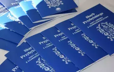 Książki &quot;Skarb Przybylskiego- ludowy haft z czarnkowszczyzny&quot; rozłożone na nakrytym obrusem stoliku
