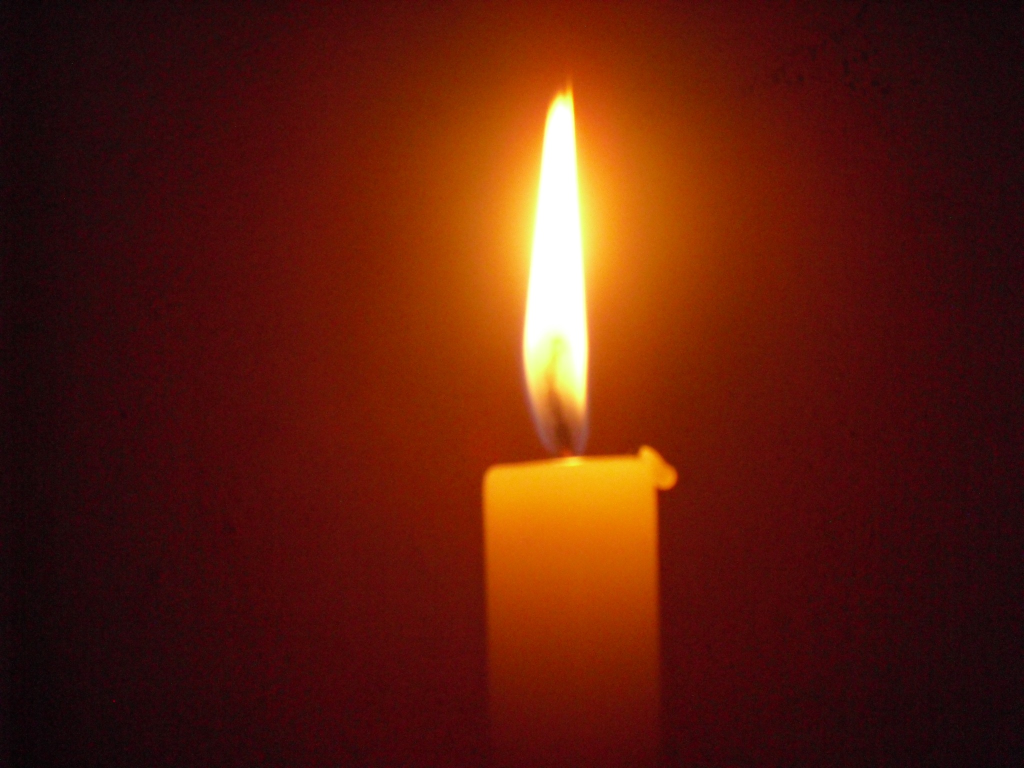 Obrzek przedstawia palącą się świecę, na czarnym tle